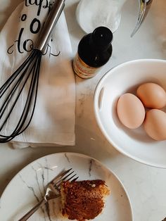 a piece of cake sitting on top of a white plate next to an egg in a bowl