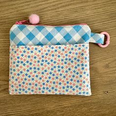 a blue and white checkered pouch with pink pom - pom on it