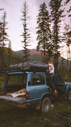 a man standing on the back of a blue truck with a tarp over it's roof