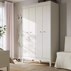 a white armoire sitting next to a window