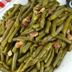 cooked green beans with bacon on top in a white plate, ready to be eaten