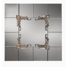 an ornate mirror with silver tiles on the wall in the shape of a rectangle