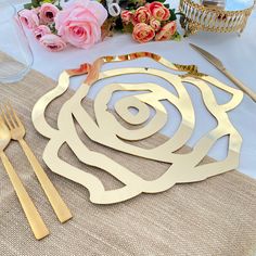 there is a place setting on the table with pink roses and gold utensils