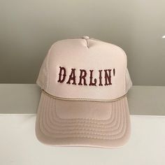 Add a touch of Southern sweetness to your style with our embroidered hat featuring the word 'DARLIN' in western script.  This classic sand colored trucker cap is perfect for anyone who loves Southern charm and effortless style with colors ready for fall! Whether you're heading to a music festival, a day out with friends, or simply want to express your playful side, this hat is a must-have accessory. Details: Color: Beige Material: Polyester Foam Front truck cap with Mesh Back adjustable straps S Vintage Adjustable Baseball Cap For Rodeo, Retro Adjustable Baseball Cap For Rodeo, Adjustable Retro Baseball Cap For Rodeo, Vintage Rodeo Baseball Cap With Curved Brim, Vintage Curved Brim Baseball Cap For Rodeo, Vintage Curved Bill Trucker Hat For Summer, Flat Brim Baseball Cap For Country Events, Adjustable Curved Brim Baseball Cap For Outdoor Events, Vintage Snapback Trucker Hat For Country Events