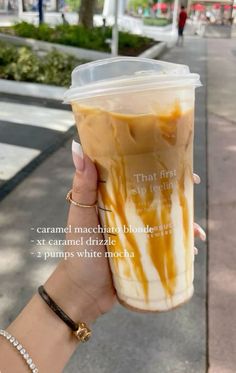 someone holding up a cup with caramel drizzle on it