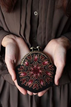 a woman is holding a purse in her hands and wearing a brown dress with pink flowers on it