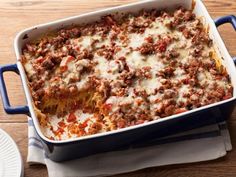 a casserole dish with meat and cheese in it sitting on a table next to a plate