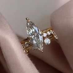 an engagement ring with a pear shaped diamond surrounded by smaller diamonds