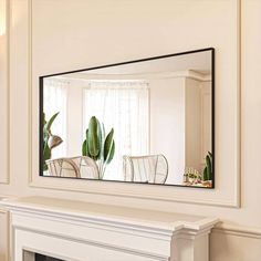 a mirror on the wall above a fireplace in a room with white walls and furniture