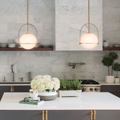 a kitchen with marble counter tops and white flowers in a vase on the center island