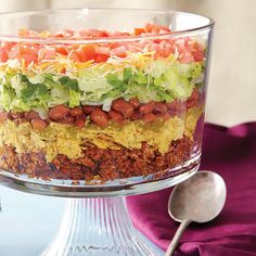 a layered salad with lettuce, tomatoes and other toppings in a glass dish