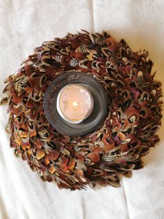 a candle that is sitting inside of a glass bowl on a tablecloth covered surface