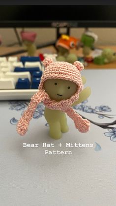 a small toy bear wearing a knitted hat and scarf on top of a table