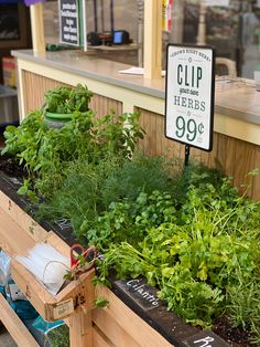 an assortment of fresh herbs on display at a farmers market with a sign reading clip herbs 99 cents