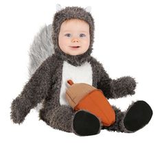 a baby dressed in a squirrel costume sitting on the ground with an orange mitt