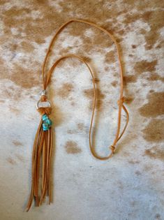 Enjoy wearing this lightweight, adjustable tassel and faux turquoise necklace. Bohemian Lariat Necklace With Tassels, Beach Jewelry With Brown Tassels, Adjustable Tassel Necklace For Festivals, Adjustable Fringe Dangle Necklace, Adjustable Lariat Tassel Necklace, Bohemian Lariat Necklace With Tassels For Gifts, Bohemian Adjustable Tassel Necklace With Fringe, Bohemian Lariat Necklace With Tassels As Gift, Turquoise Tassel Necklace For Beach