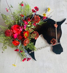 a black horse with flowers on it's head and a chain around its neck