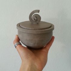 a hand holding a gray pot with a spiral handle