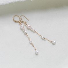 Expertly crafted for the modern bride, these long gold-filled earrings feature genuine pearls and a sleek, handcrafted design. Elevate any ensemble with these timeless, sophisticated accessories. - Handcrafted with genuine freshwater pearls. - Gold filled chain pictured - Gold plated earring wire with CZ stones - Available in gold filled, rose gold filled or rhodium (silver). - Earrings measure 3 inches - Nickel free and hypoallergenic This is an original design by © Treasures by Agnes PLEASE ALLOW APPROX 7 BUSINESS DAYS FOR COMPLETION MATCHING PIECES: https://www.etsy.com/listing/1777474326/pearl-back-necklace-for-wedding-bridal?click_key=736c66cfe217b2bc273a13effc42d9c42fcd5d2e%3A1777474326&click_sum=a139307c&ref=shop_home_active_1&pro=1&frs=1&sts=1 https://www.etsy.com/listing/179165355 White Long Drop Pearl Earrings In 14k Gold Filled, White Long Drop Pearl Earrings In 14k Gold, Gold Linear Earrings With Pearl Charm For Wedding, Delicate Long Drop Pearl Earrings In 14k Gold, Minimalist 14k Gold Filled Linear Earrings For Wedding, Delicate Yellow Gold Bridal Earrings With Pearl Drop, Yellow Gold Drop Linear Earrings For Wedding, Minimalist Pearl Drop Wedding Earrings, Pearl White Dangle Earrings For Wedding