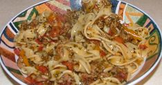 a plate full of pasta with meat and vegetables on it, ready to be eaten