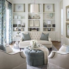 a living room with white furniture and blue accents