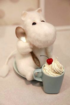 a small white mouse sitting on top of a cup filled with whipped cream and a cherry