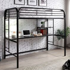 a loft bed with a desk underneath it in front of a brick wall and potted plant