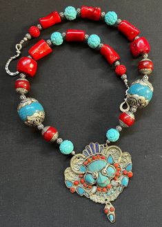 "Antique Himalayan filigree Nepalese turquoise and coral pendant beaded with carved turquoise beads and red coral gemstone beads with red capped Nepalese silver beads.  Beaded with 6 beautiful blue carved turquoise beads that are about 18mm and added 2 big blue capped Tibetan beads that measure approximately 30mm and 4 red capped Nepalese beads that are 16mm.  I added chunky bright red delicious coral beads that range in size from 16mm up to 26mm.   The silver filigree spacer beads measure about 5mm. The Himalayan filigree pendant measures 4\" in width by 4\" in height and has been in my studio for many years. I finally decided on the beads to use and I am happy with the result.  The necklace measures 24\" in length. I finished it with an antique antique silver hook clasp closure.  You wil Traditional Beaded Necklace With Red Coral And Natural Stones, Artisan Red Carved Jewelry, Traditional Red Carved Necklace, Bohemian Turquoise Necklace With Red Coral, Bohemian Turquoise Necklace With Red Coral For Gift, Bohemian Red Coral And Turquoise Jewelry, Bohemian Turquoise And Red Coral Necklaces, Bohemian Turquoise And Red Coral Necklace, Bohemian Red Coral Beaded Necklace In Turquoise