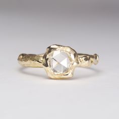 a gold ring with a white diamond in it's center, on a gray background