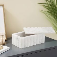 a white marble box sitting on top of a table next to a candle holder and mirror