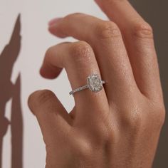 a woman's hand with a diamond ring on her finger and the shadow of an object behind her