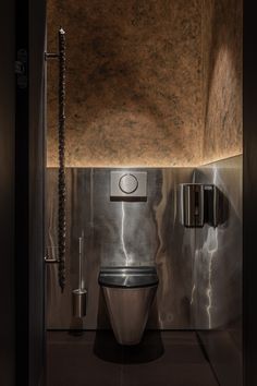 a bathroom with a metallic toilet in the middle of it's walls and lighting on either side