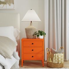 a bedroom with an orange dresser next to a white bed