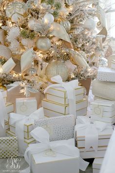 a christmas tree with white and gold presents in front of it, surrounded by gifts