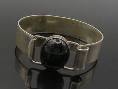 MEXICO 925 Sterling Silver - Vintage Black Onyx Hook Bangle Bracelet - BT6143  MEXICO 925 Sterling Silver - Vintage Black Onyx Hook Bangle Bracelet - BT6143  Jewelry Type:         Bracelet   Metal Type:            925 Silver  Metal Size:             6.25" Length  .50" Height   Stone Type:            Onyx   Condition:              N/A  Jewelry Weight:     37.4 Grams  PLEASE NOTE: THIS ITEM IS PRE-OWNED. ALTHOUGH MOST ITEMS ARE IN VERY GOOD CONDITION, SOME MAY NEED CLEANING AND/OR MINOR REPAIRS. W Contemporary Adjustable Formal Jewelry, Formal Black Polished Cuff Bracelet, Formal Black Cuff Bracelet With Polished Finish, Black Polished Cuff Bracelet For Formal Occasions, Modernist Sterling Silver Adjustable Bracelet For Formal Occasions, Modern Onyx Bracelet Jewelry, Modern Onyx Bracelet, Formal Black Round Sterling Silver Bracelet, Formal Black Sterling Silver Round Bracelet