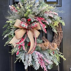 a christmas wreath on the front door with pine cones, berries and evergreens tied to it