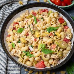 a bowl filled with pasta salad next to tomatoes