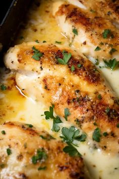 some chicken is cooking in a pan with cheese and parsley on the top of it