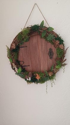 a round wooden sign hanging on a wall with plants and leaves around it, in the shape of a circle