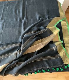 Black Linen Saree with zari borders with green piping along with a zari striped pallu finished with green tassels.  Comes with a linen unstitched blouse. Readymade blouse is displayed for styling purposes only. If you want to buy them they are in the blouse section or message us. Festive Linen Traditional Wear With Zari Work, Festive Traditional Linen Wear With Zari Work, Traditional Wedding Saree With Tassels, Traditional Linen Saree With Zari Work, Festive Linen Dupatta With Zari Work, Festive Linen Saree With Pallu Detail, Wedding Linen Saree With Handloom Detail, Green Bollywood Dupatta With Tassels, Festive Wedding Linen Saree