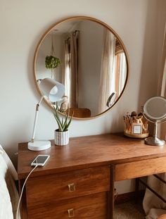 a wooden desk with a mirror and lamp on it