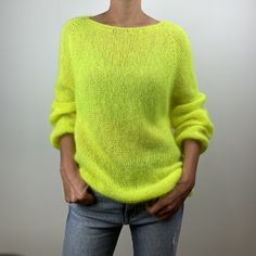 a woman wearing a bright yellow sweater and jeans stands with her hands in her pockets