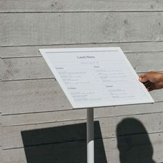 a person standing next to a sign with a hand on it's index board