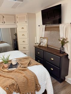 a bedroom with a bed, dresser and television