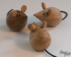 three wooden mouses sitting next to each other on a white counter top with black cord