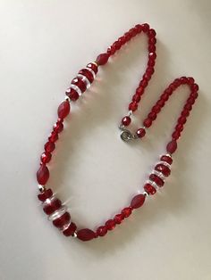 This unique red and white striped clear glass faceted bead necklace has three sections of mixed beads including mat red glass beads and clear disk beads with silver spacers. The fun necklace is beautifully strung. The larger beads are 12mm with the smaller ones in the back being 5mm. The necklace is 18 1/2 inches long. I specialize in finding fun wearable jewelry. Please browse my shop for more fun options. I box sales ready to be given as gifts. I often combine multiple item purchases to save o Red Rondelle Beaded Necklace With Spacer Beads, Red Rondelle Single Strand Beaded Necklace, Red Rondelle Beaded Jewelry, Red Rondelle Jewelry With Large Beads, Red Rondelle Beaded Necklace Single Strand, Red Crystal Necklaces With Faceted Beads For Jewelry Making, Red Glass Beaded Necklaces With Polished Beads, Red Faceted Crystal Necklaces For Jewelry Making, Adjustable Red Crystal Necklaces With Colorful Beads