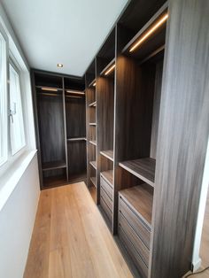 an empty walk - in closet with wooden shelves and drawers