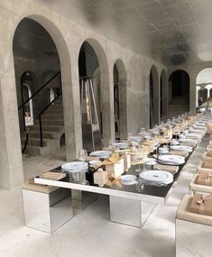 a long table with many plates and silverware on it in a room that has arches