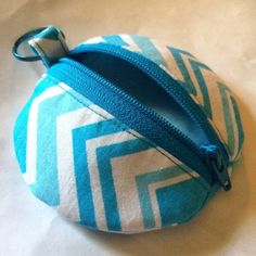 a blue and white zippered pouch sitting on top of a bed next to a keychain