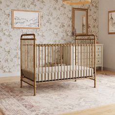 a baby crib in the corner of a room with floral wallpaper on the walls